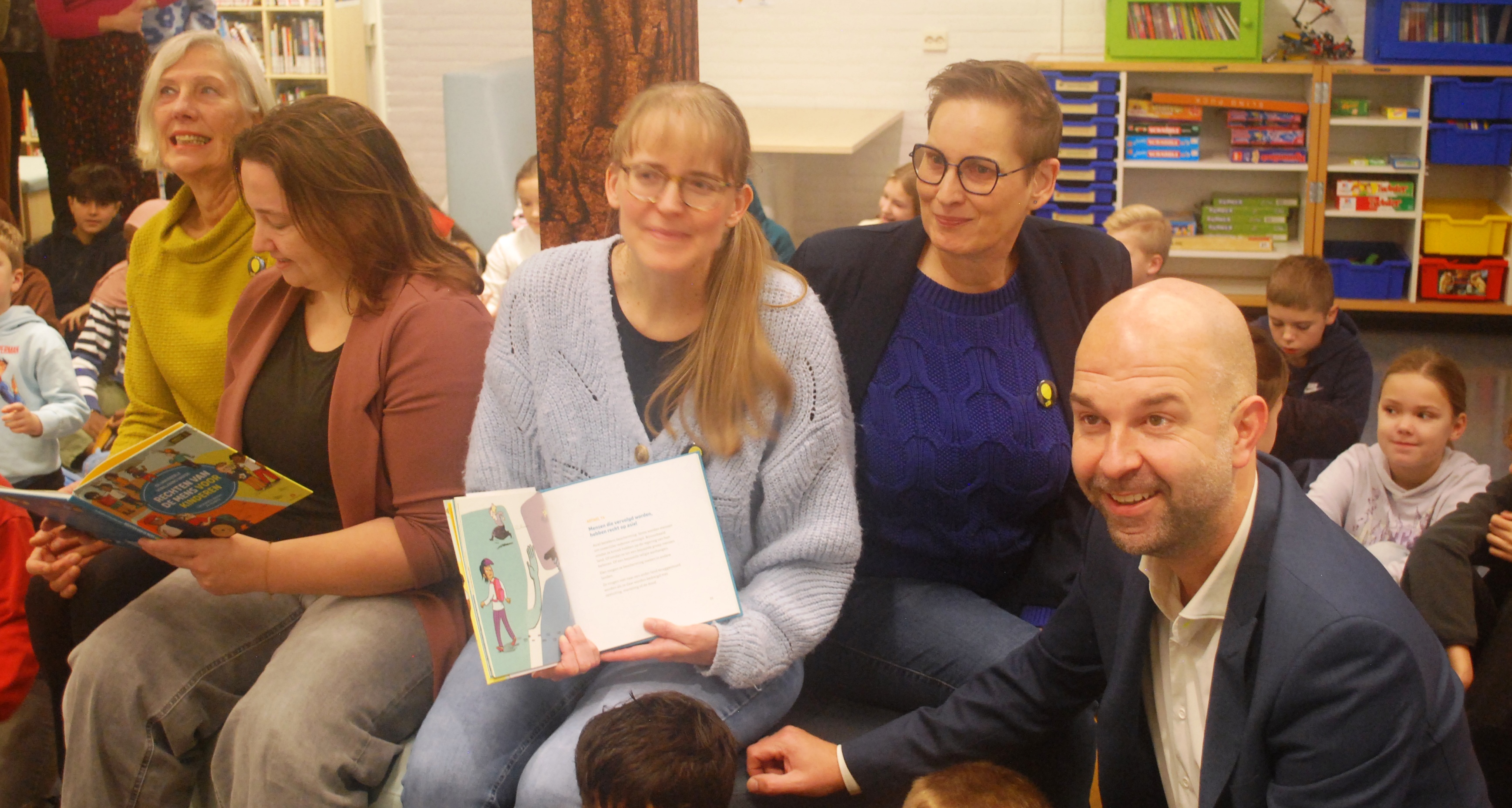 Te midden van alle leerlingen van ODBS ’t Kienholt: de overhandiging van het boek aan Directeur Linda Pereboom (tweede links), in aanwezigheid van wethouder Mark Tuit (rechts) door werkgroepleden Aya Wolting (links), Hilde Kerssies (midden) en Marika Hemmen-Groen (tweede rechts). groep